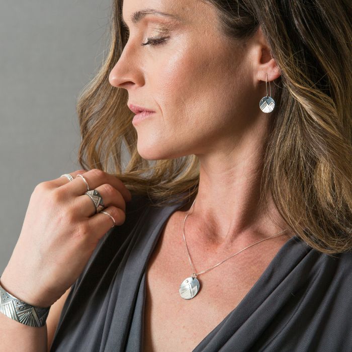 Model wearing silver mountain necklace with gold moon