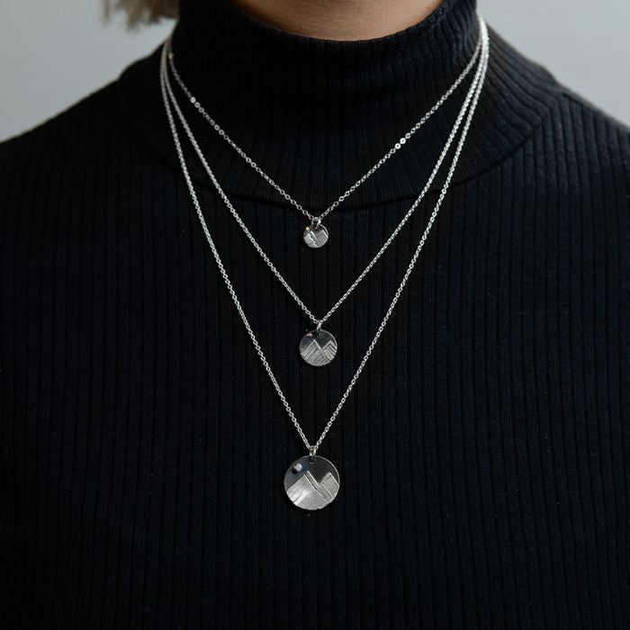 Model wearing silver mountain charm necklace
