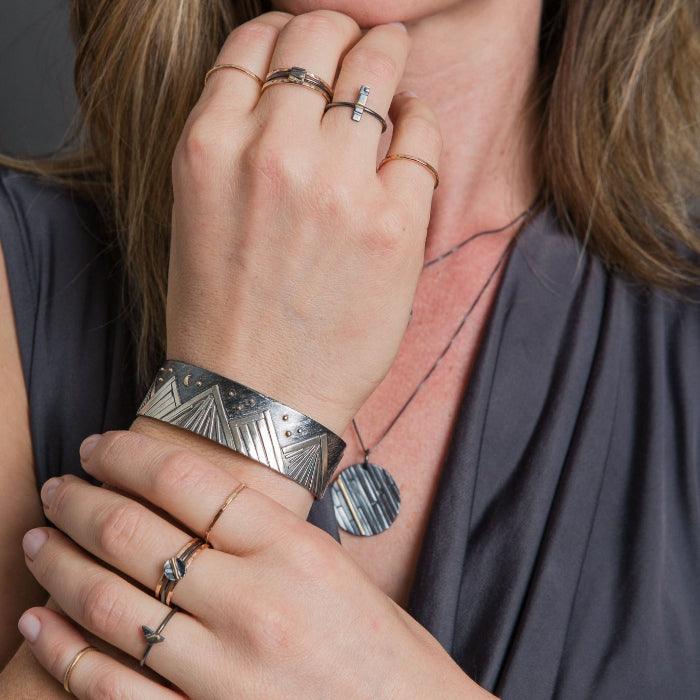 Model wearing mountain bracelet in sterling silver and gold