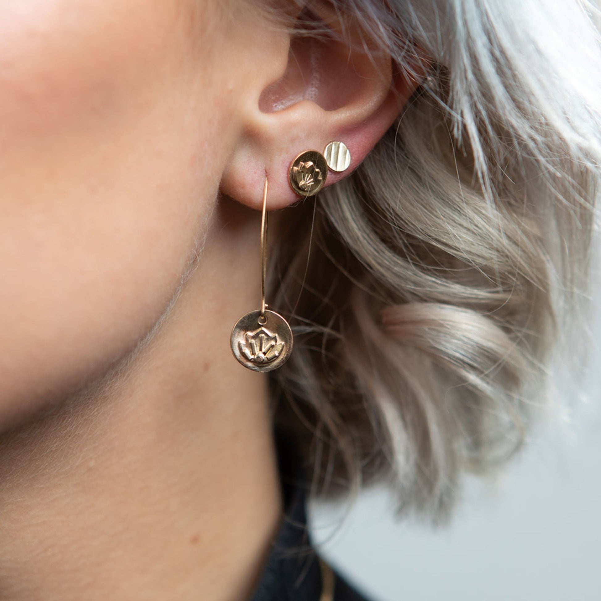 Close up of model wearing gold mini disc stud earring