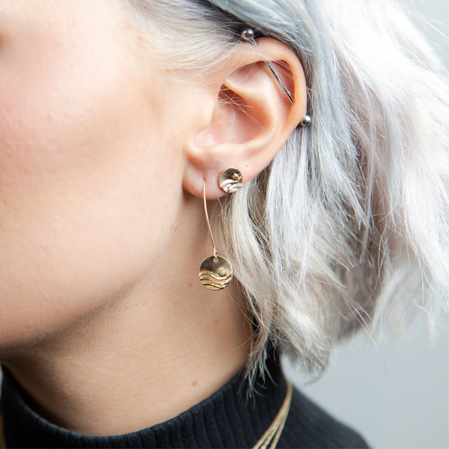 Closeup of model wearing gold reflections wave earrings
