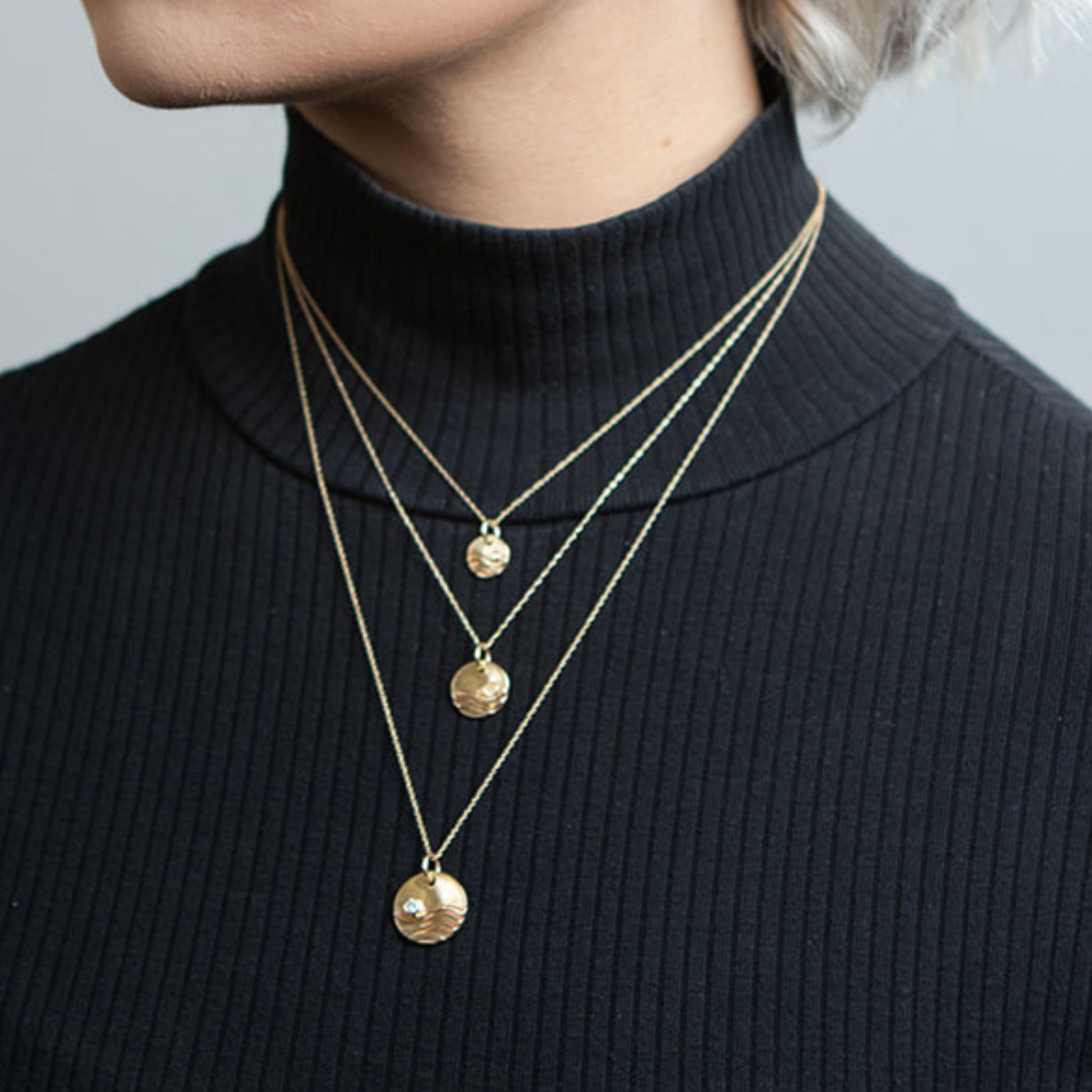 Closeup of model wearing gold reflections wave necklaces