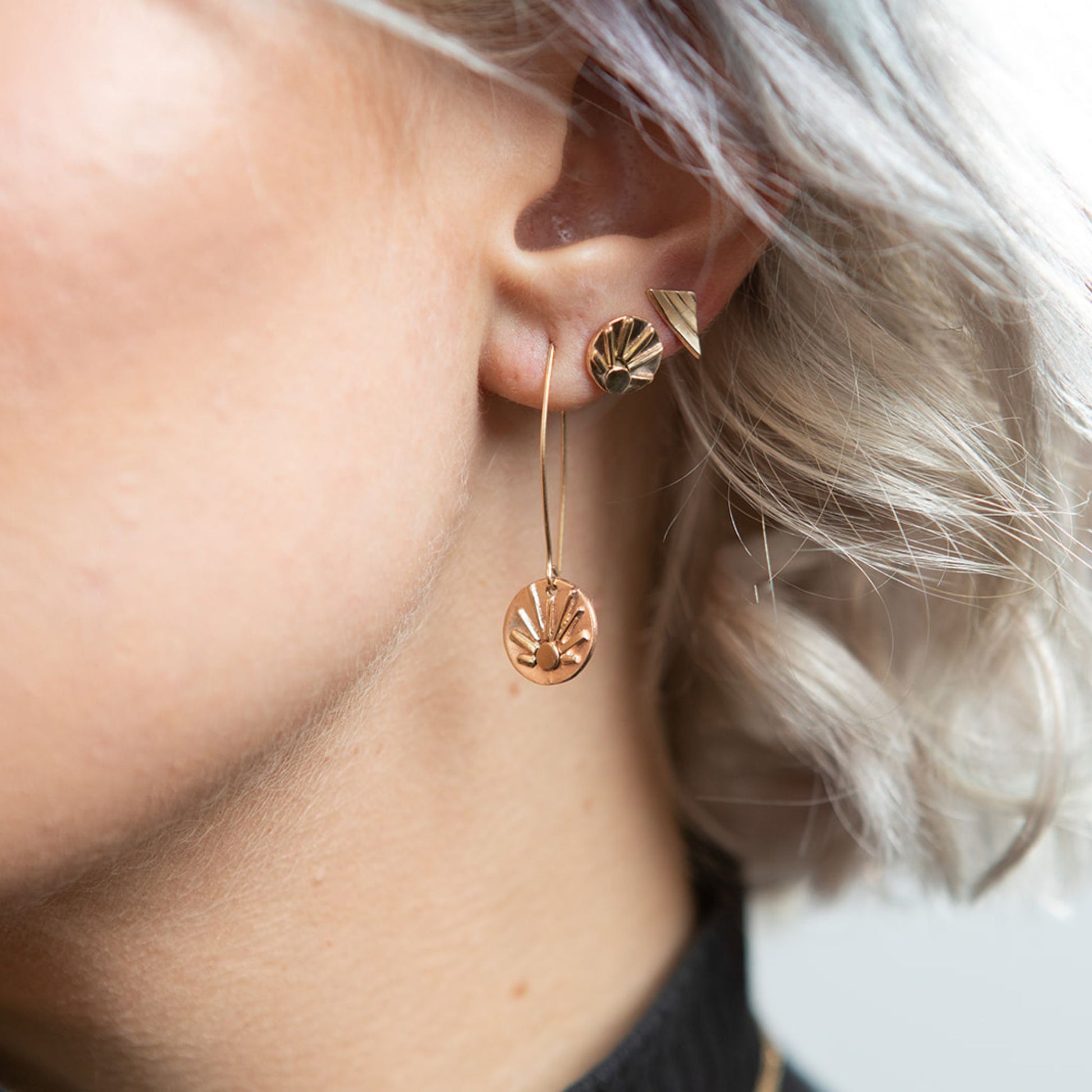 Closeup of model wearing gold triangle stud earrings
