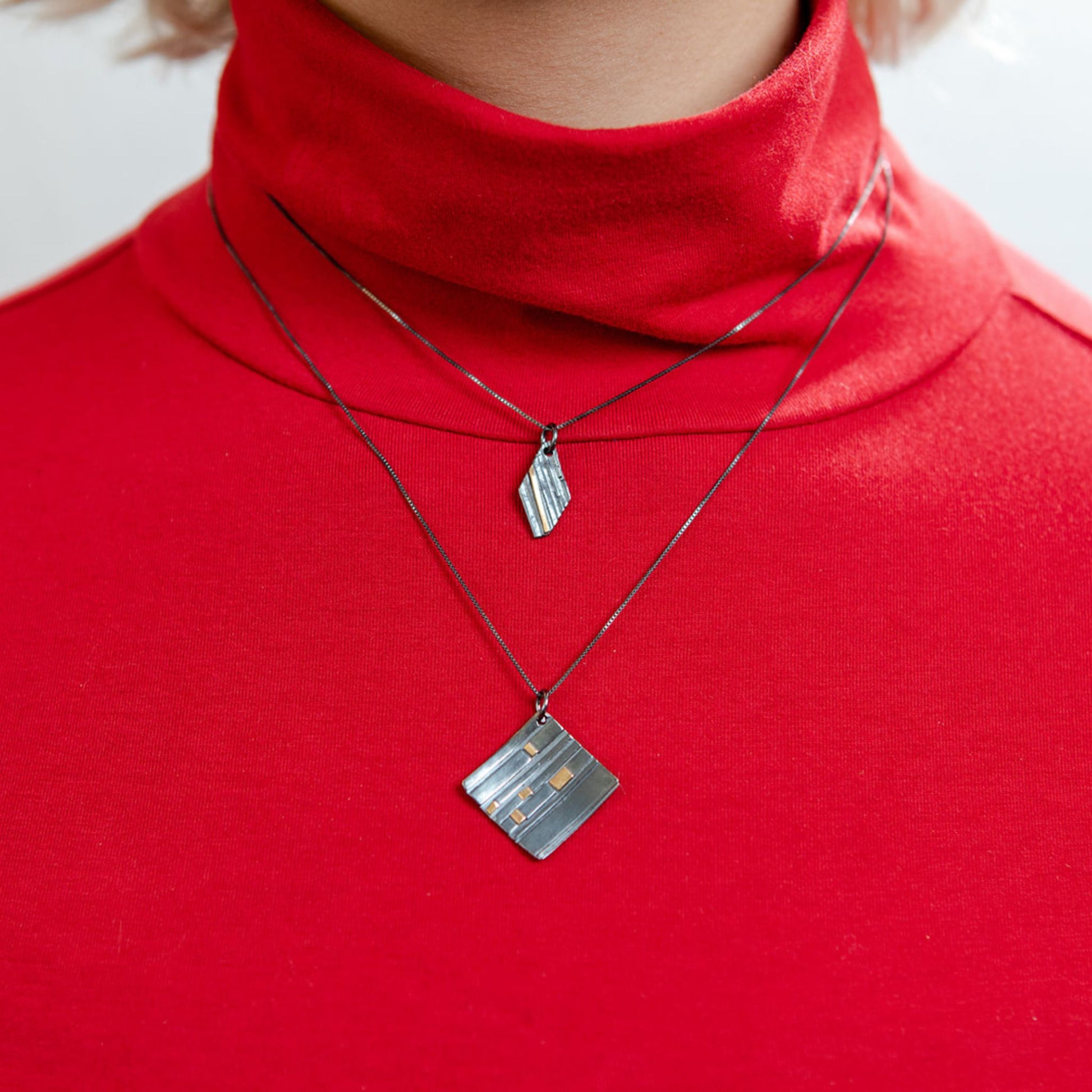 Closeup of model wearing mixed metal rhomboid necklace oxidized