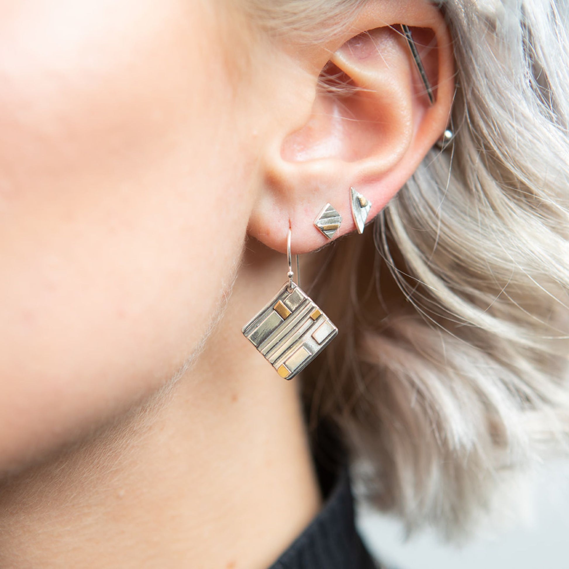 Closeup of model wearing mixed metal triangle stud earrings