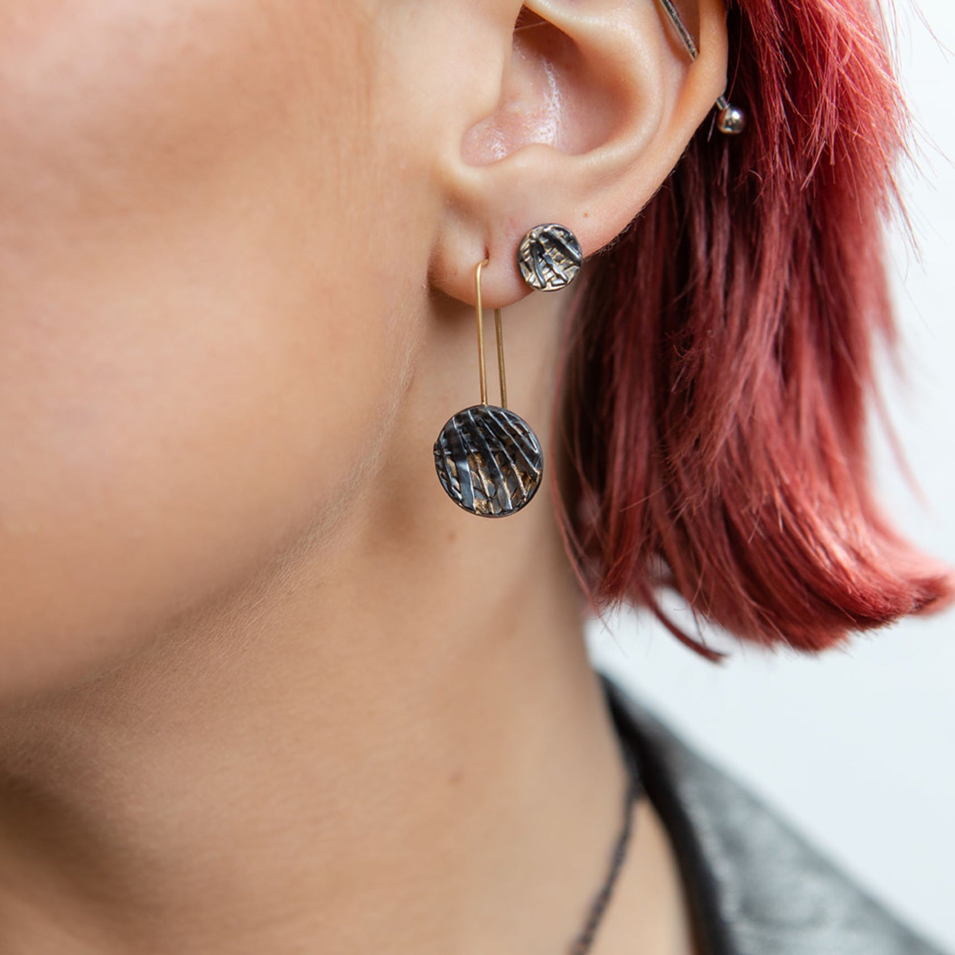Coin mixed metal earrings close up on model