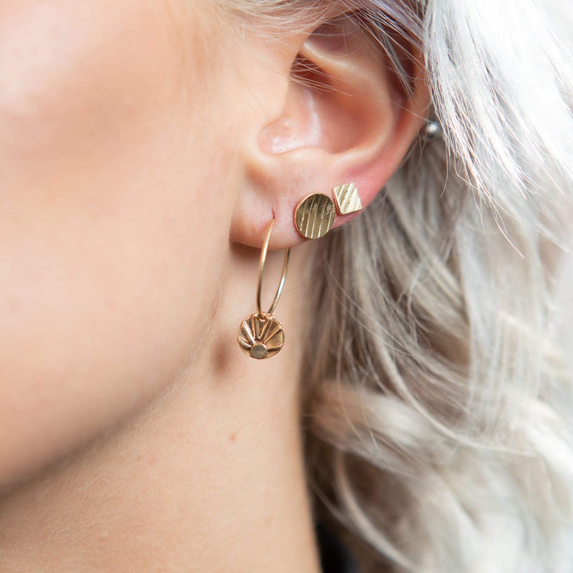 Model wearing gold disc stud earrings