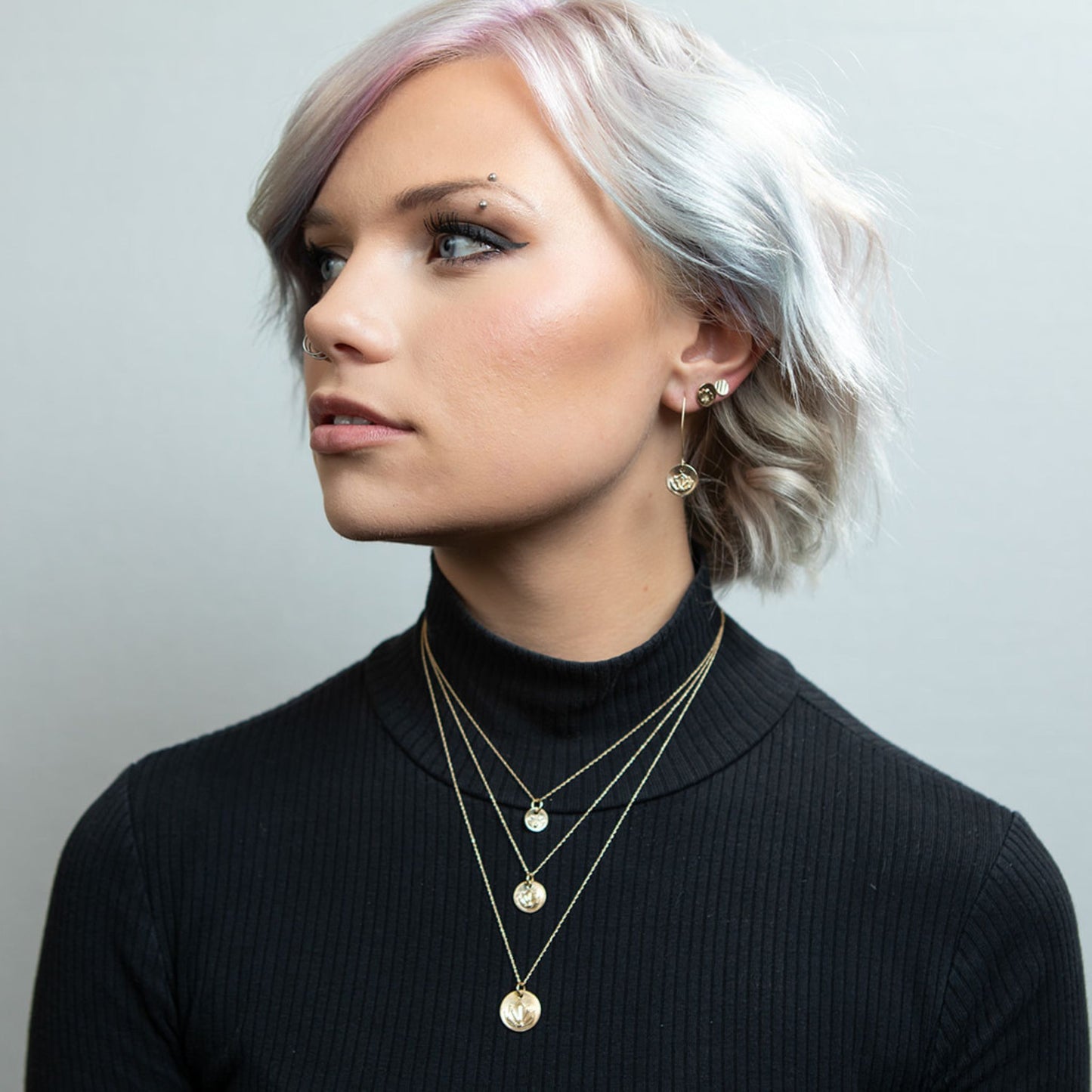 Model wearing gold mini disc stud earring