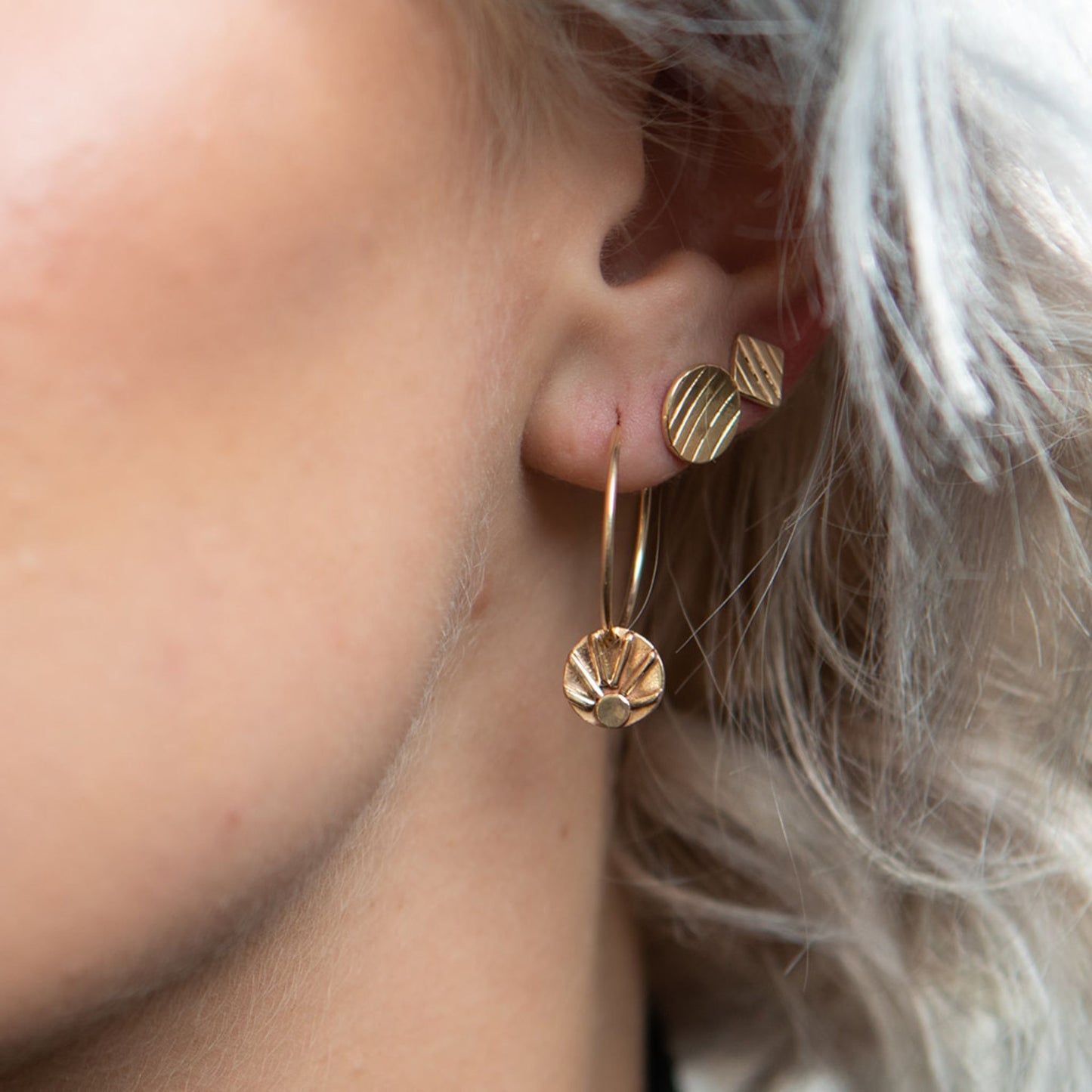 Model wearing gold square stud earrings