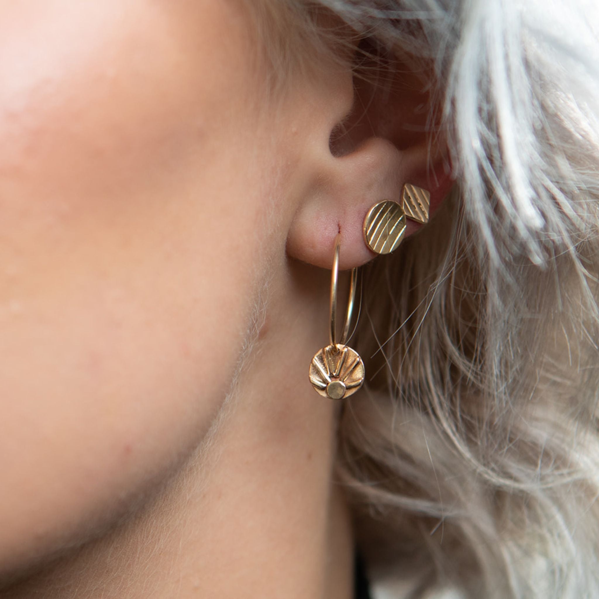 Model wearing gold square stud earrings