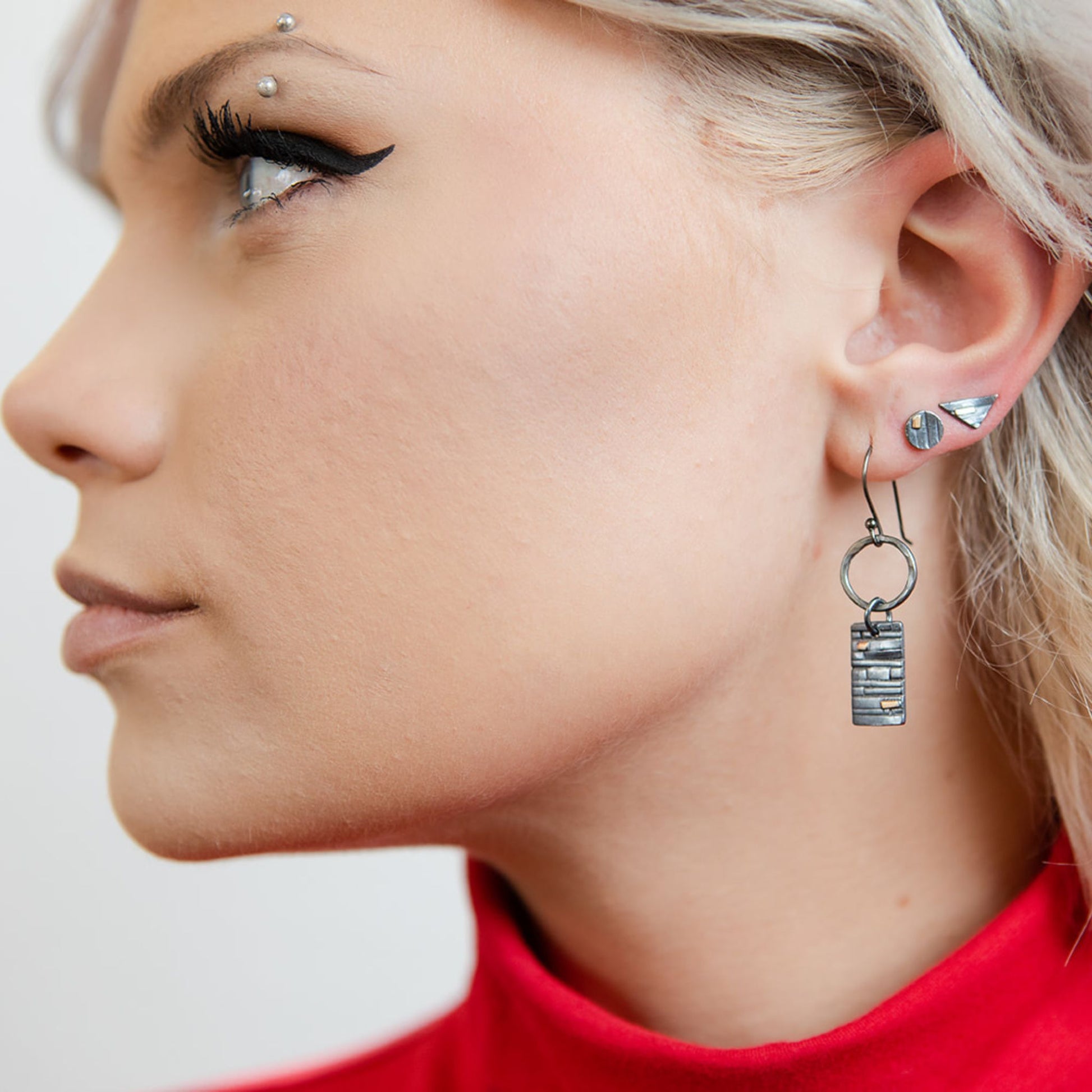 Model wearing oxidized triangle stud earrings