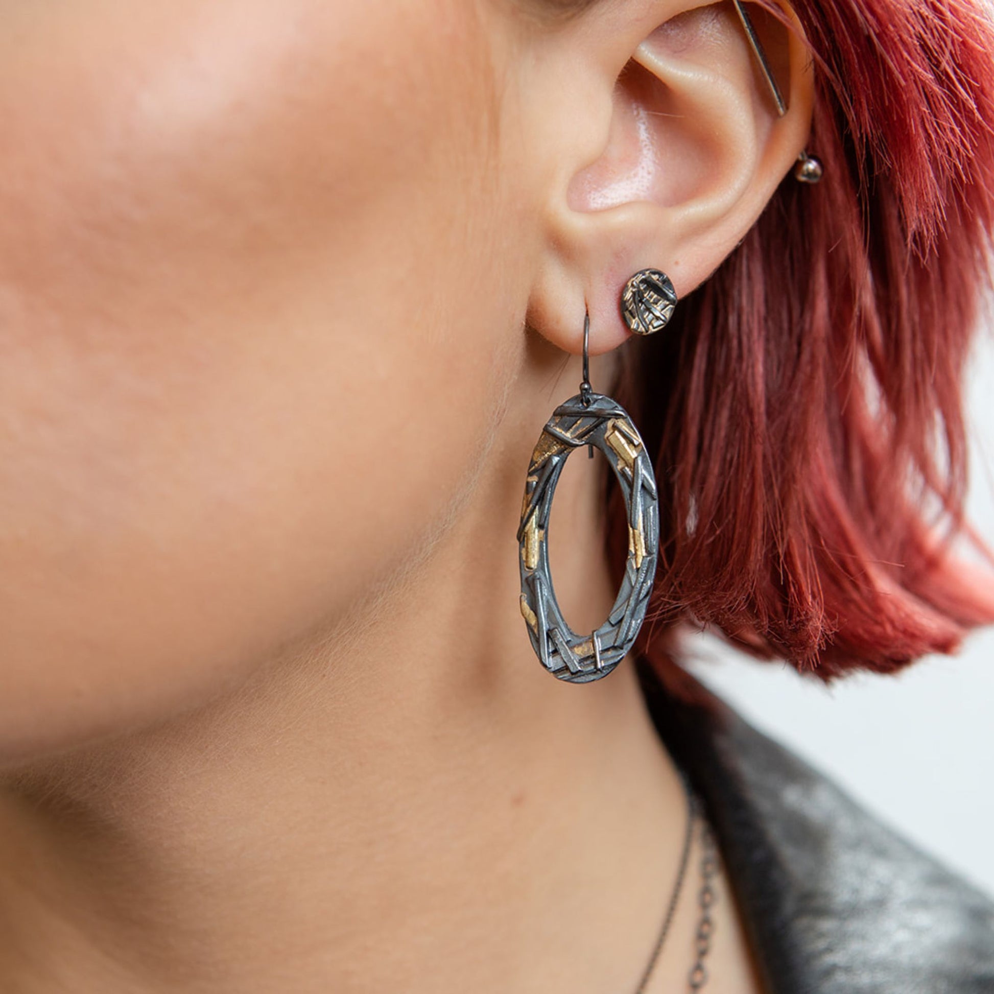 Oval mixed metal earrings close up on model